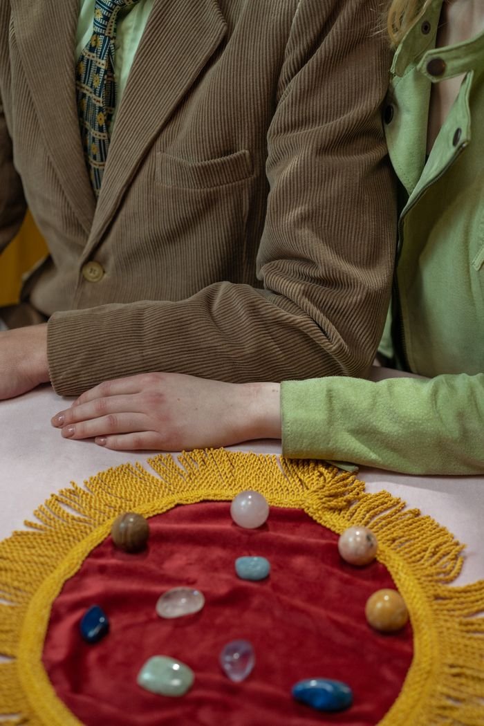 services-02 Close-up of a couple with arms touching, displaying gemstones on a vibrant cloth. Vintage ambiance.